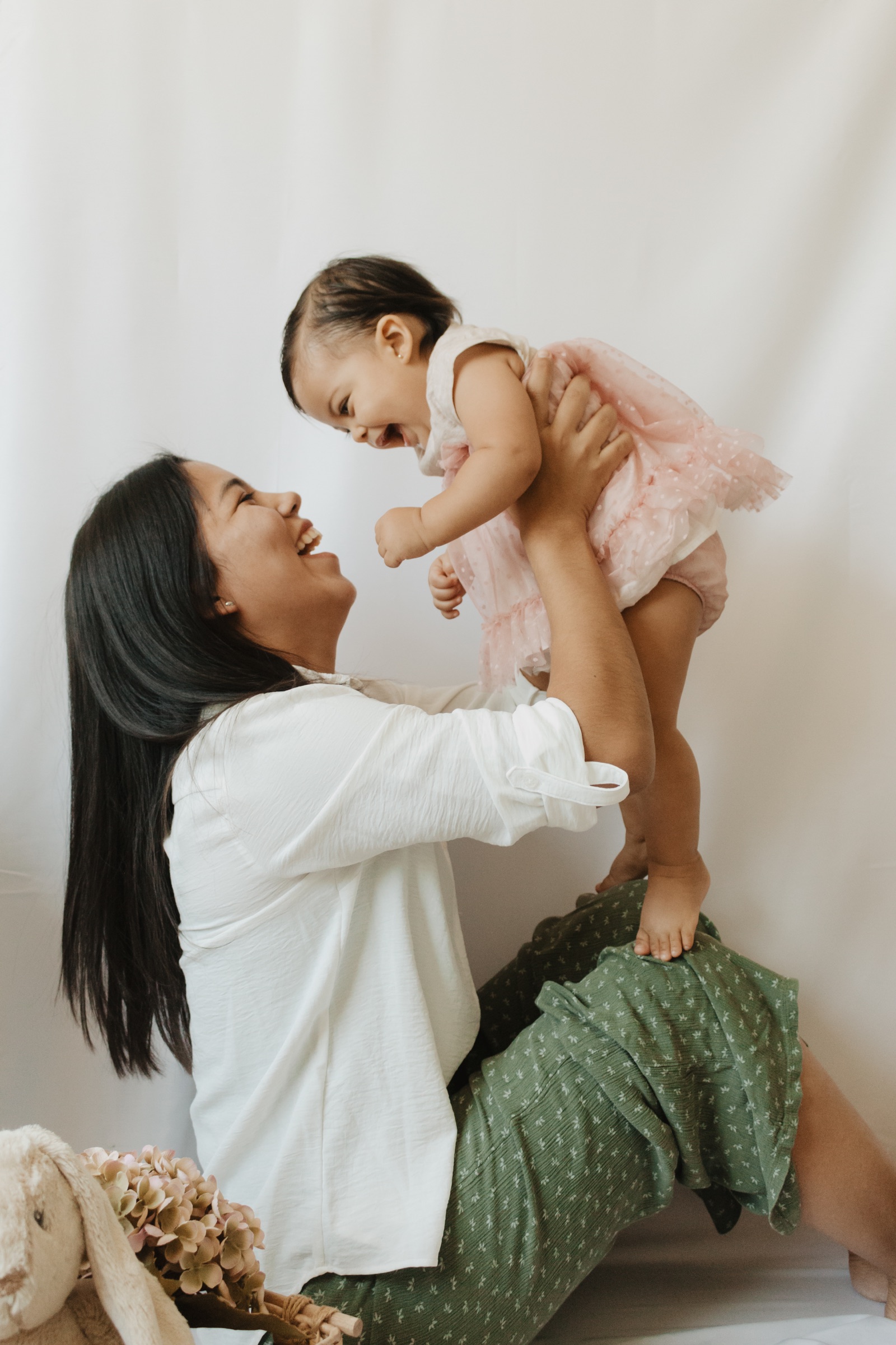 Madre sosteniendo a su bebé y sonriendo durante una sesión familiar