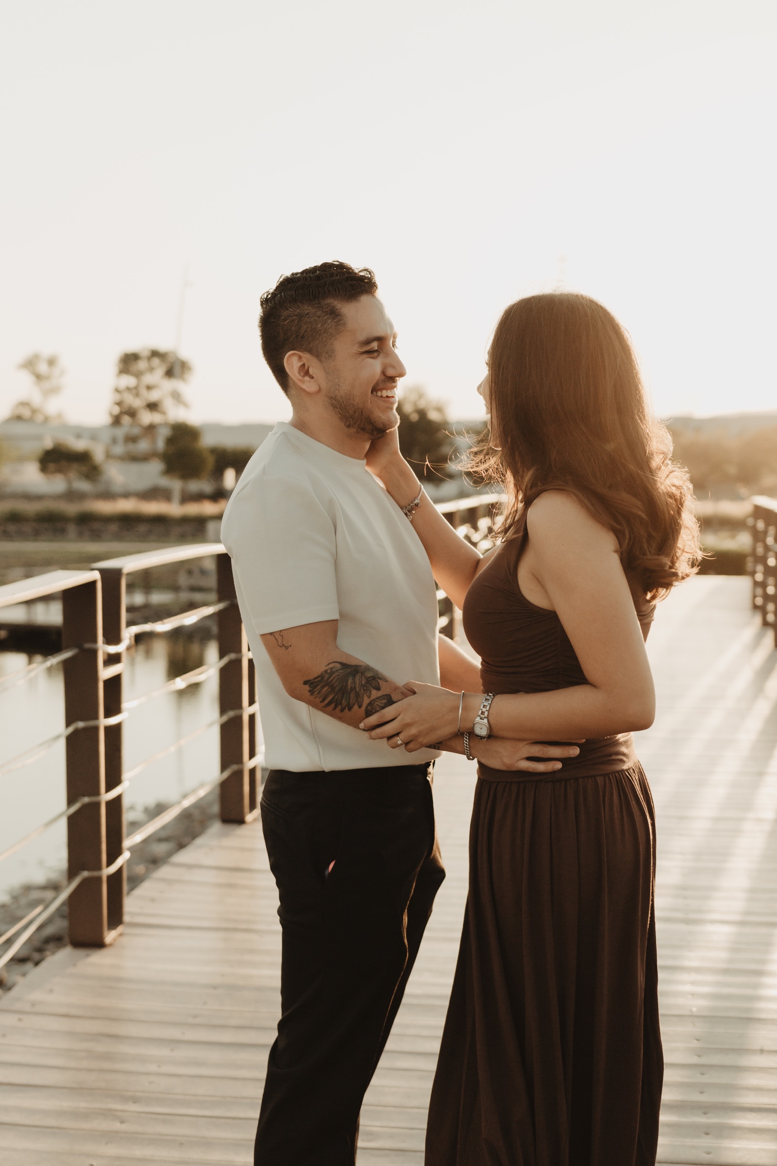 Pareja mirándose y sonriendo durante una sesión al atardecer