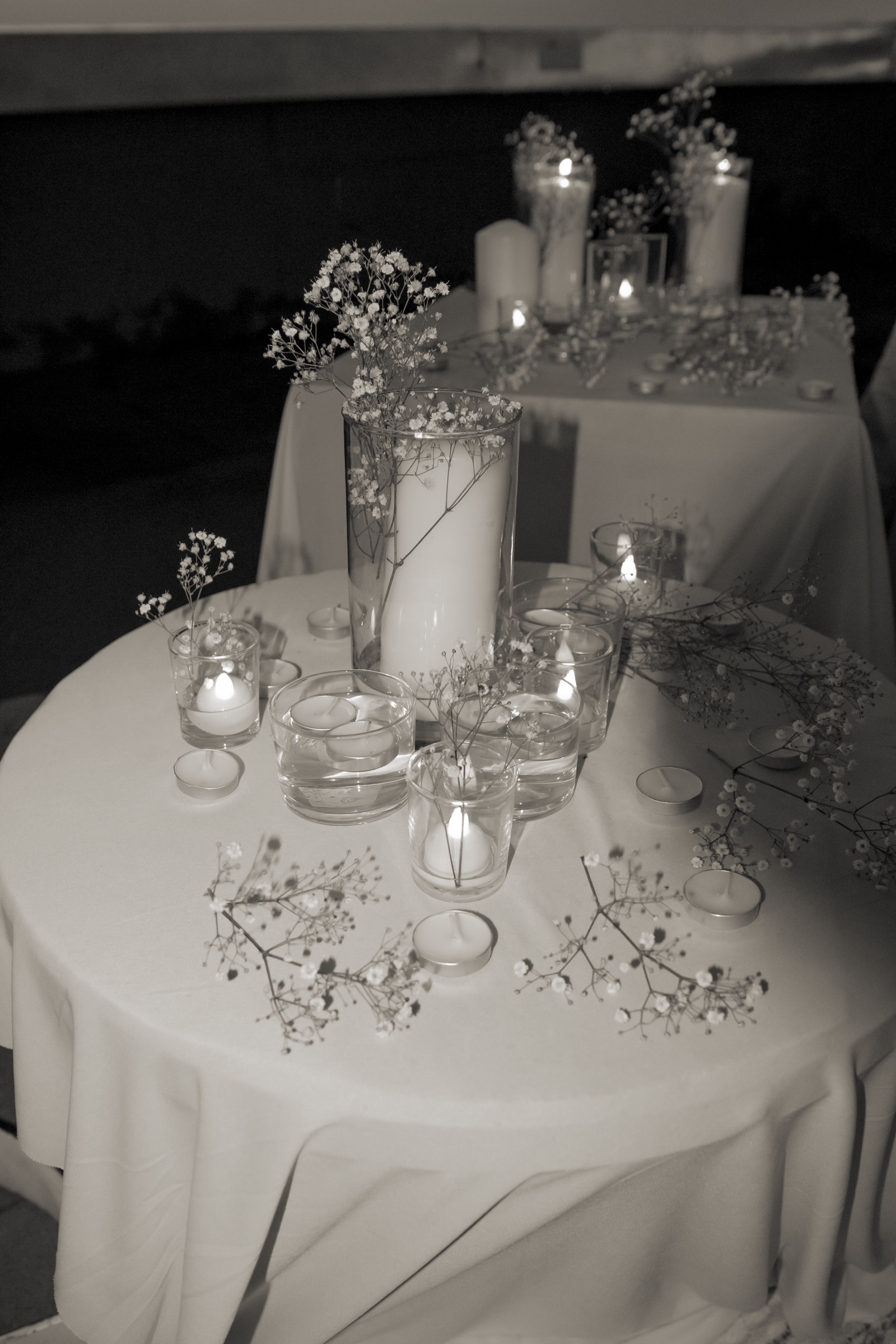 Composición de velas y flores blancas sobre una mesa, en blanco y negro